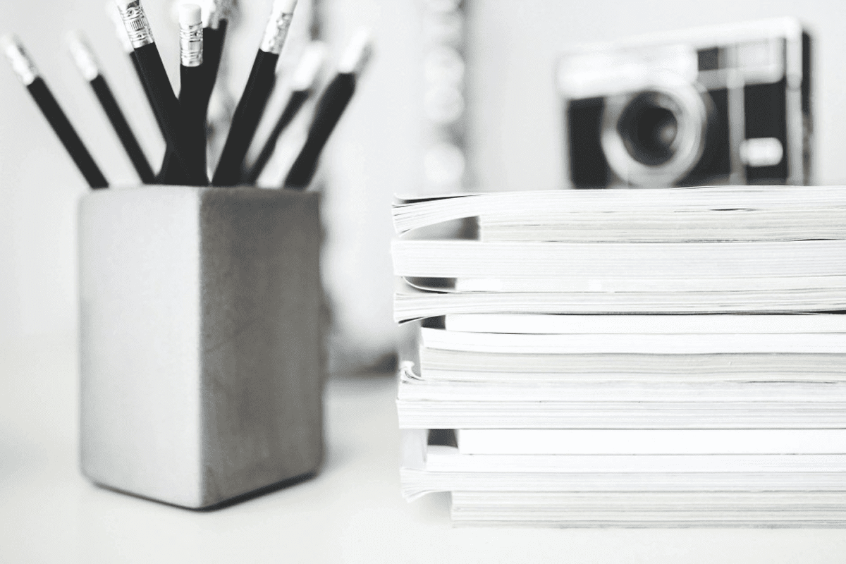 Pencils in holder, stack of magazines nearby.