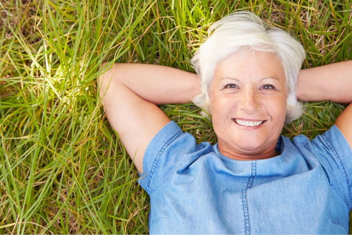 Smiling woman lying on grass outdoors.