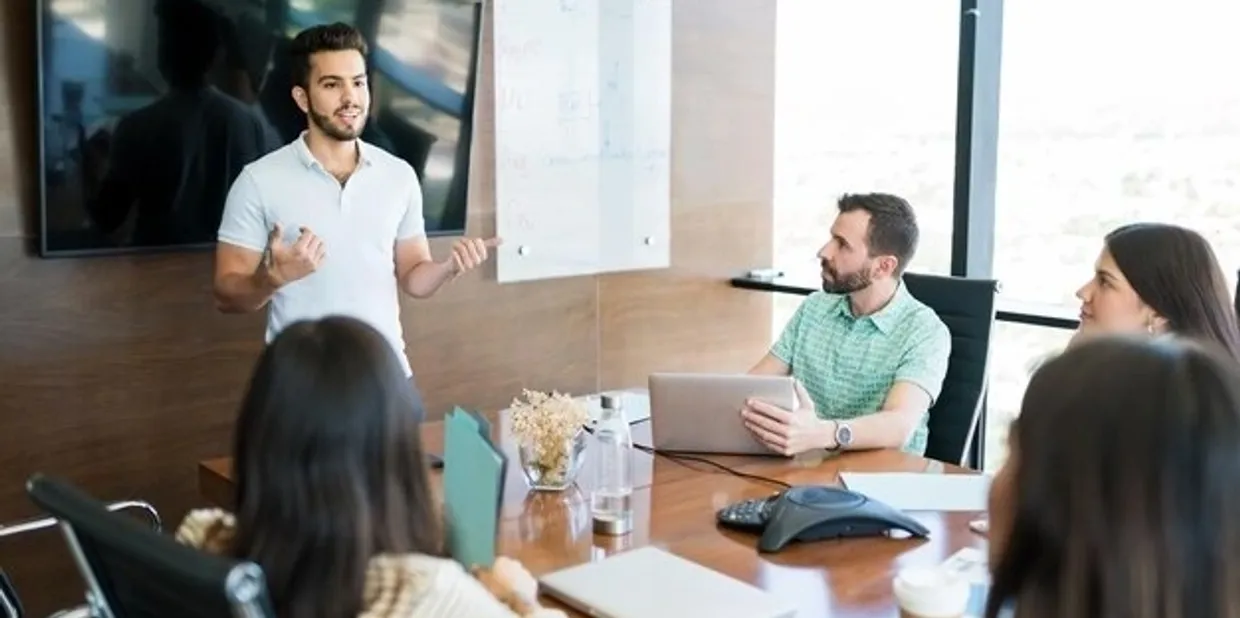 A man presenting to colleagues in a modern office meeting.