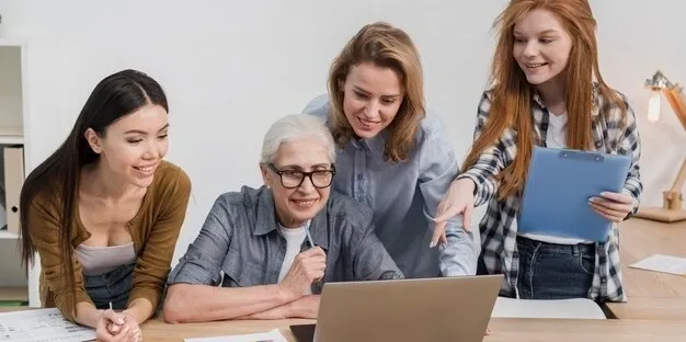 Three women happily collaborating over a laptop.